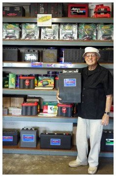 An older man standing in front of a wall of batteries