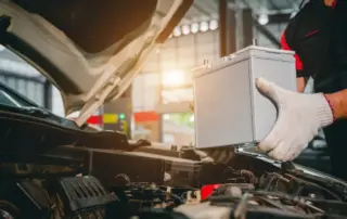 A mechanic replaces a car battery